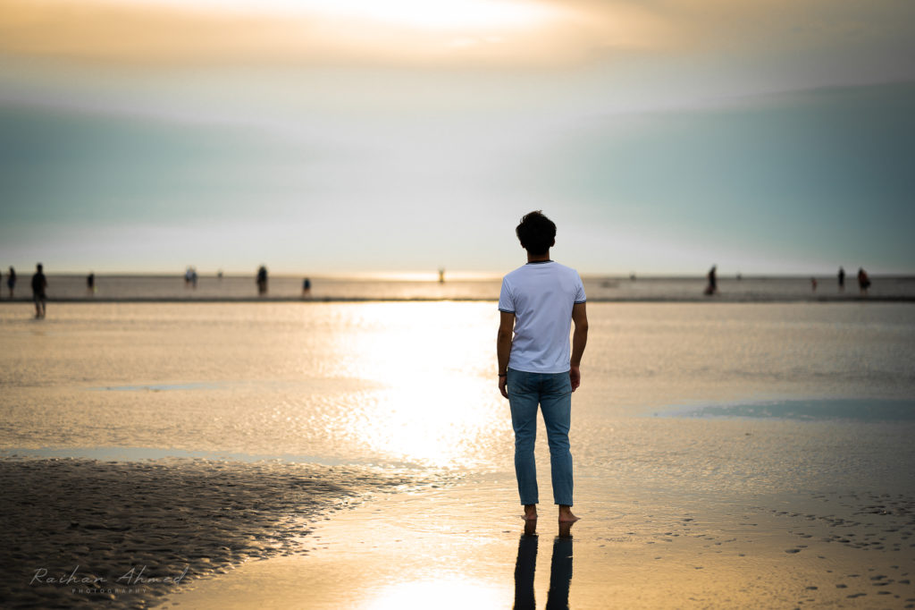 Man standing at the beach with sunset in background