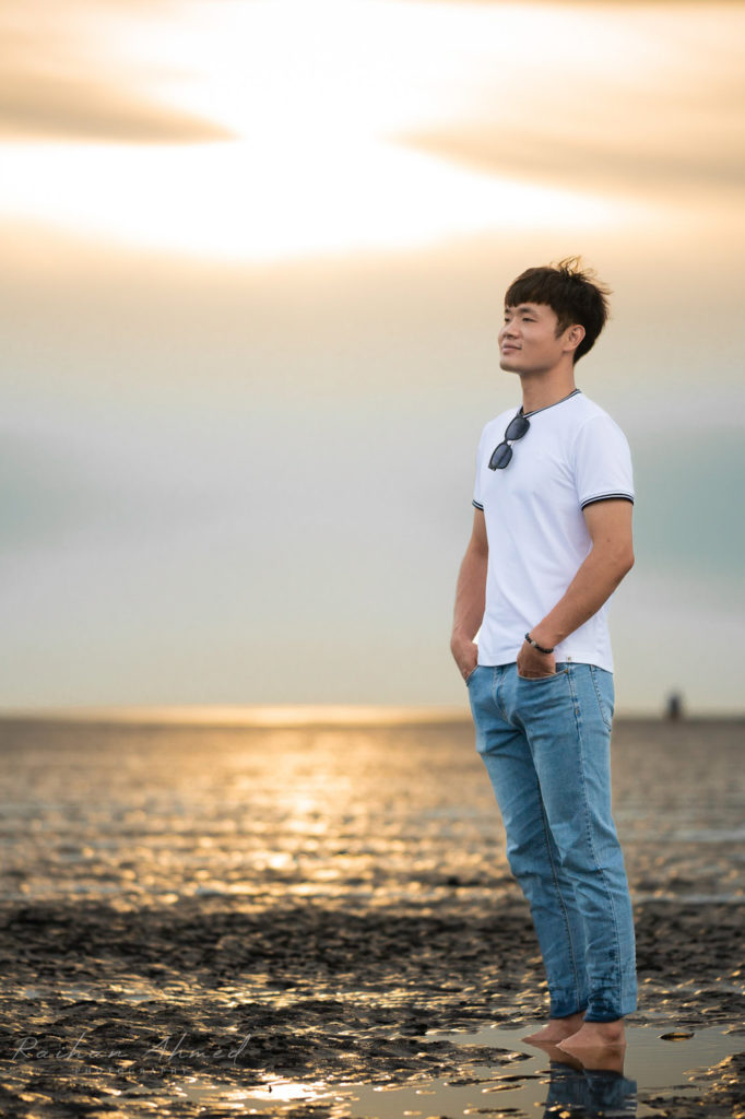 Man with sunset in background stands at the beach