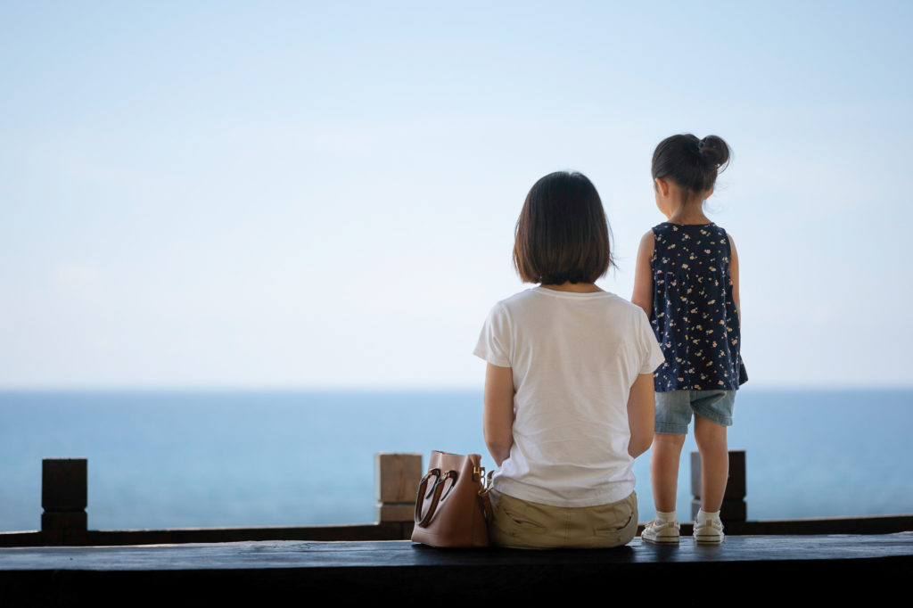 Photo of a mother and daughter looking out into ocean