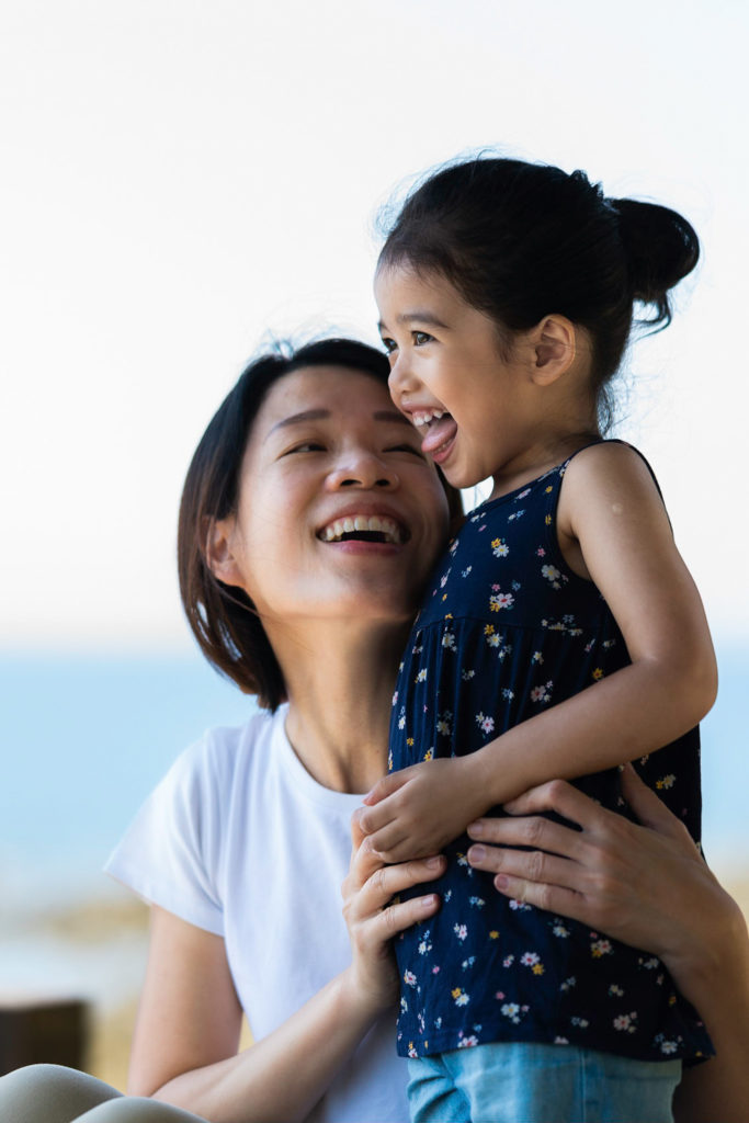 Photo of a toddler laughing and mother looking at toddler
