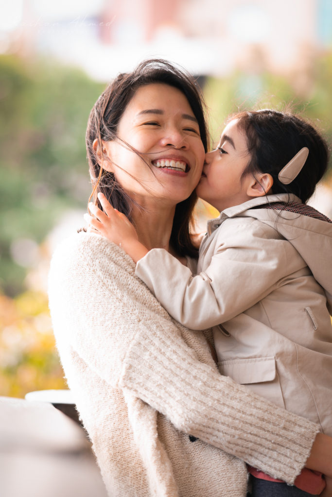 Photo of a mother being kissed by daughter.