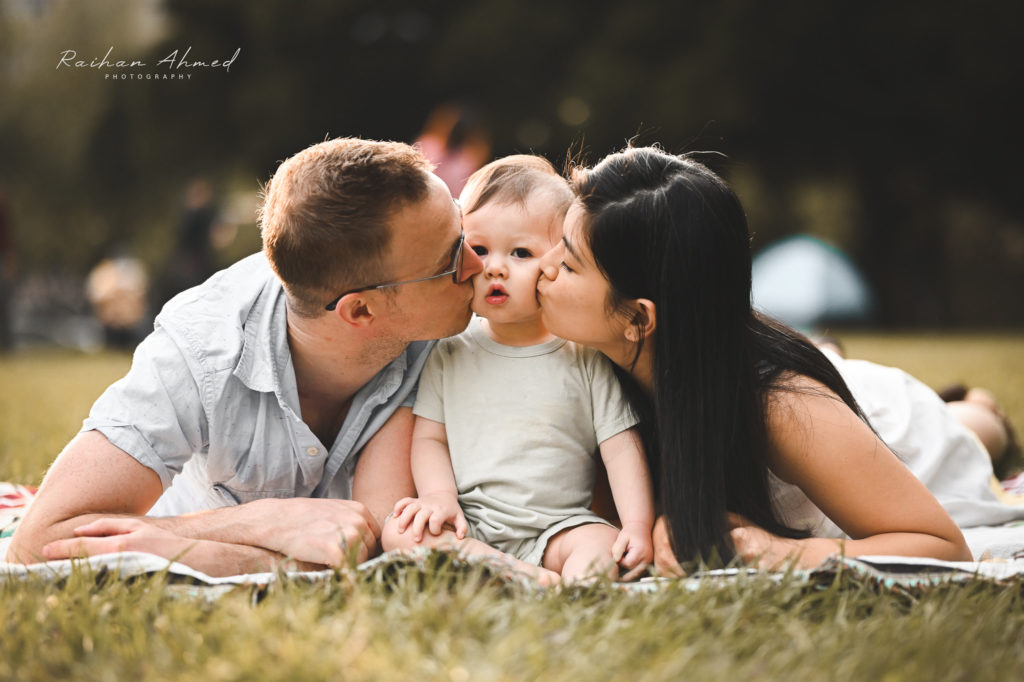 Photo of a father and mother kissing their son