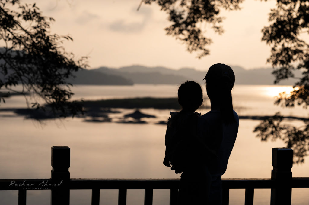 Photo of a mother and daughter silhouette at a lake.