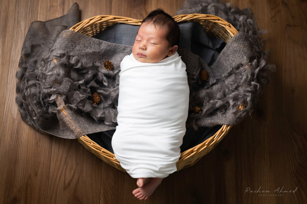 Photo of a newborn baby lying in a heart shaped basket.