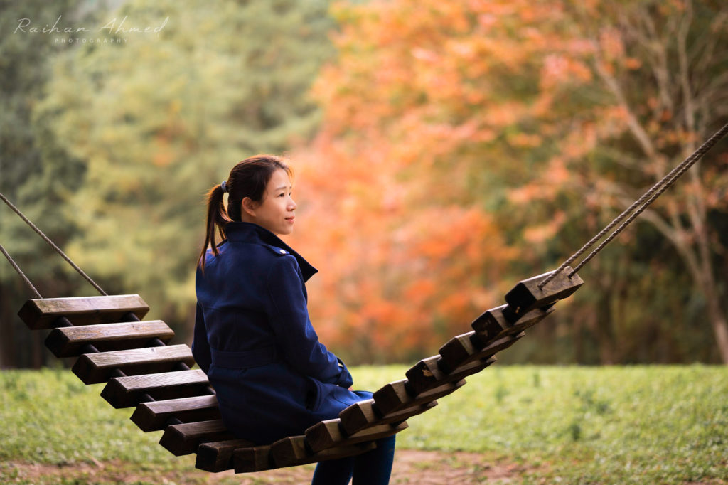 Woman sitting on wooden hammock looking away