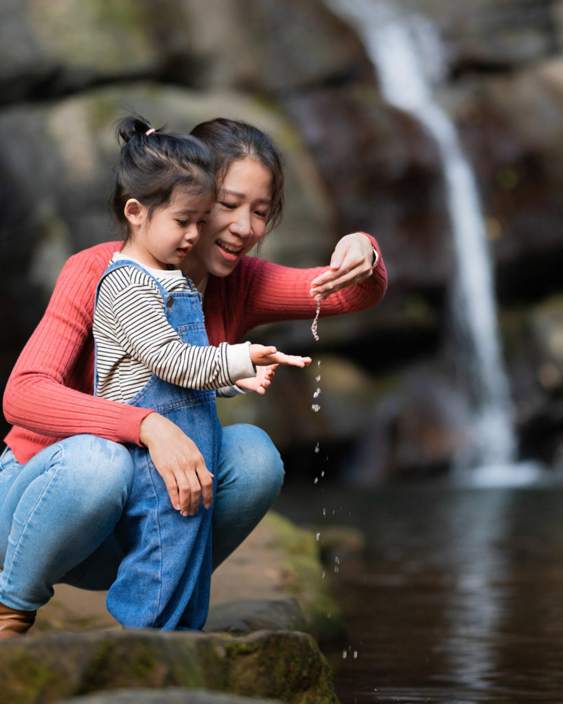 Photo of a mother and daughter beside a waterfall