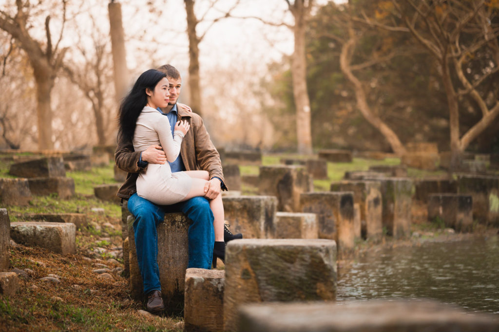 Photo of a woman sitting on man's lap looking at a lake