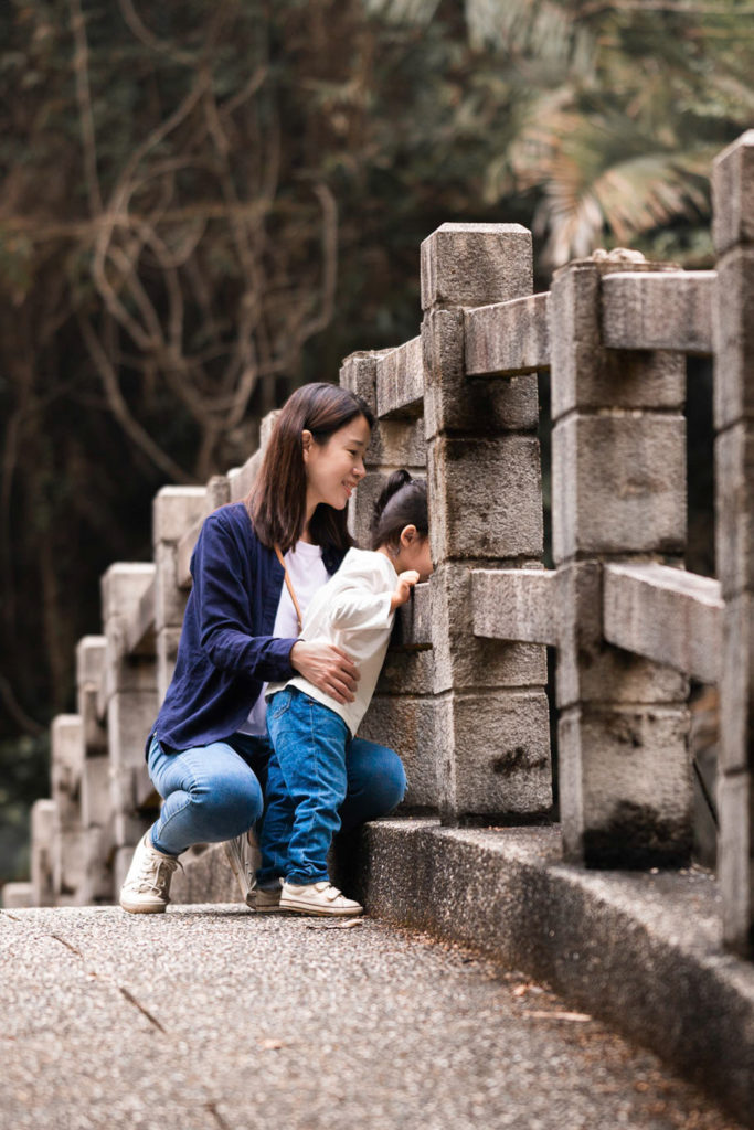 Photo of a mother and daughter looking through a forest bridge