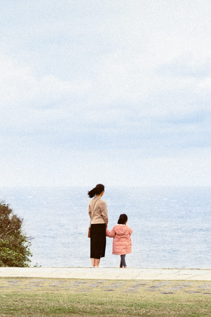Mother and daughter looking out at ocean