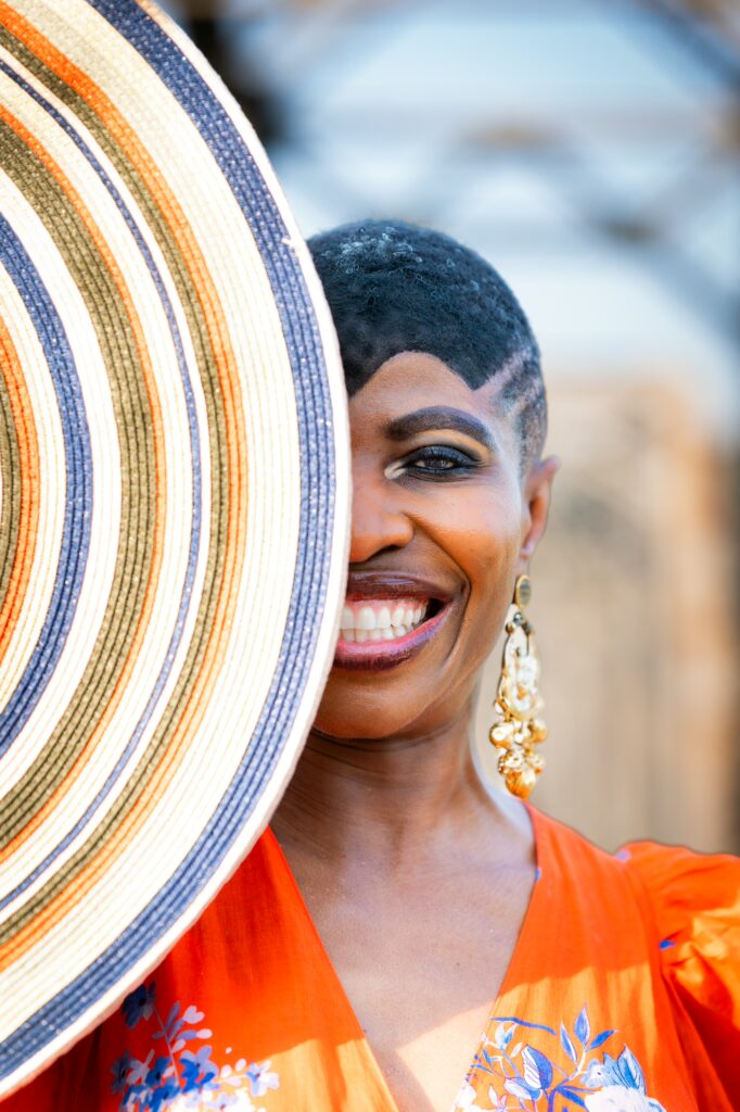 Woman, half face covered by hat, smiling